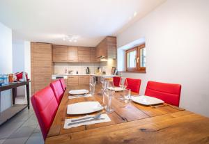 a wooden table with red chairs and a kitchen at Vallemaggia Green House in Sornico +25 photos