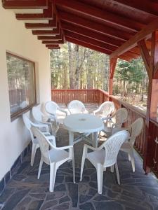 a patio with white tables and chairs on a deck at Fenyves Home in Izvoare