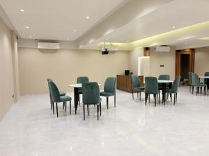 a room with tables and green chairs and a kitchen at Hotel Avenue Inn in Navi Mumbai
