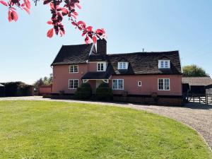 a pink house with a grassy yard in front of it at Cottage Farm by The Suffolk Cottage Collection in Offton