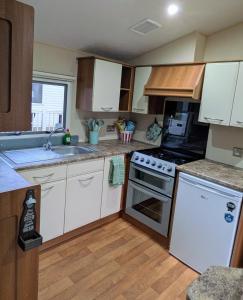 a kitchen with white cabinets and a stove top oven at 26 The Meadows in Tattershall +6 photos