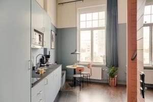 a kitchen with white cabinets and a table and a window at The Nooq Malmö - Hotel & Studios in Malmö