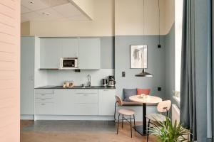 a kitchen with white cabinets and a small table at The Nooq Malmö - Hotel & Studios in Malmö