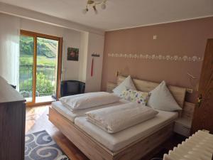 a bedroom with a bed with white sheets and a window at Weingut Pension Gibbert-Pohl in Briedel