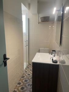 a white bathroom with a sink and a shower at L'instant cocon in Beaumont