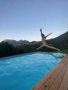 a woman jumping into a swimming pool at Ebenhof in Collepietra
