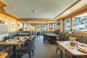 a restaurant with wooden tables and chairs and windows at Haus Melitta in Lech am Arlberg