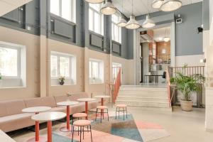 a lobby with tables and chairs and a staircase at The Nooq Malmö - Hotel & Studios in Malmö