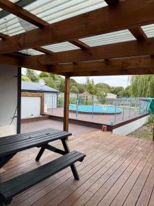 a wooden deck with a bench and a swimming pool at Otaihanga Getaway in Paraparaumu