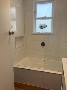 a bathroom with a shower with a window and a tub at Otaihanga Getaway in Paraparaumu +10 photos
