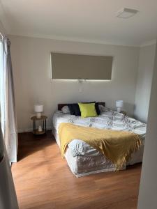 a bedroom with a bed with a yellow blanket on it at Otaihanga Getaway in Paraparaumu