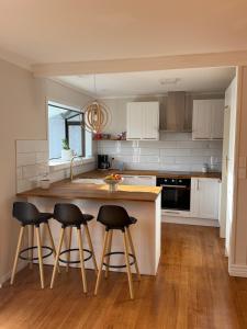 a kitchen with white cabinets and black bar stools at Otaihanga Getaway in Paraparaumu