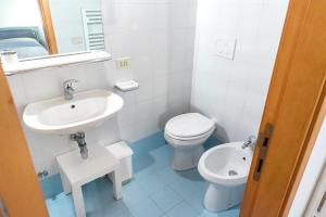 a white bathroom with a sink and a toilet at Casa Cortese Sirolo in Sirolo +3 photos