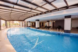 a large swimming pool with blue water in a building at Apartments in Navi in Gonio