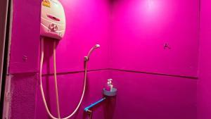 a pink bathroom with a pink wall with a phone at Pink Kraken Hostel in Ban Nong Chaeng