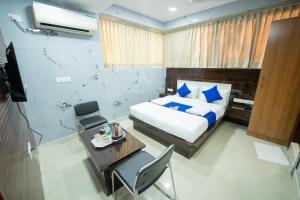 a bedroom with a bed and a table and a television at Sri Sai Saara Inn in Bangalore
