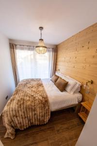 a bedroom with a large bed with a wooden wall at Morzine Centre Apartment 1 min from Super M in Morzine