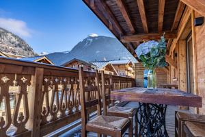 a table on a balcony with a vase of flowers at Morzine Centre Apartment 1 min from Super M in Morzine +14 photos