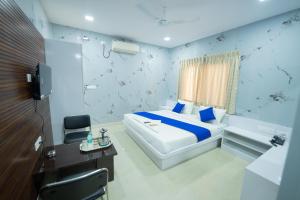 a bedroom with a bed and a desk and a television at Sri Sai Saara Inn in Bangalore