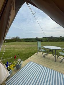 a tent with a table and chairs on a deck at Country PUPkins Camping in Branscombe