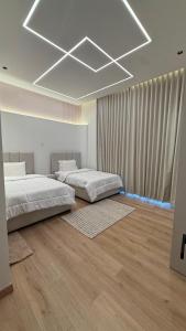 two beds in a white room with wooden floors at إستراحة نمارق in Al ‘Aqar