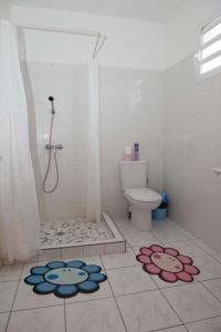 Ein Badezimmer mit Dusche, Toilette und Blumen auf dem Boden in der Unterkunft Casa Sergio in Le Moule