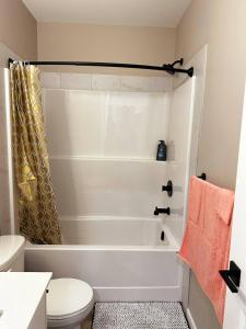a bathroom with a white tub and a toilet at Private, Cozy, Luxury, Spacious One Bedroom Suite in Airdrie