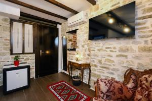 a living room with a couch and a tv on a stone wall at Guest House Nina in Berat