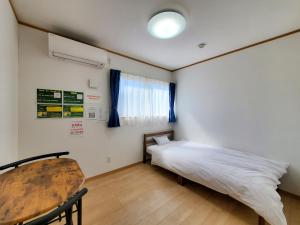 a small bedroom with a bed and a table at ゲストハウスはまなす亭 in Jōnai