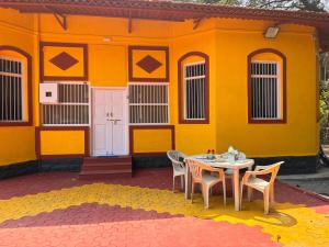 a table and chairs in front of a yellow building at Lilly Beach House in Kīhīm