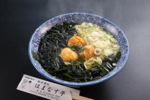 a bowl of soup with noodles and vegetables on a table at ゲストハウスはまなす亭 in Jōnai