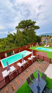 an image of a swimming pool with chairs and a table at Pousada Encantos do Rosa in Imbituba