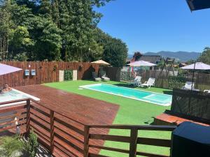 a backyard with a wooden fence and a swimming pool at Pousada Encantos do Rosa in Imbituba