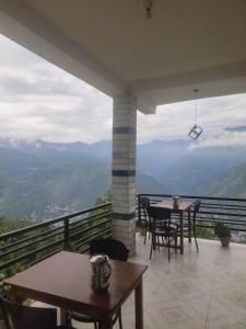 a balcony with tables and chairs and a view at Devansh Homestay &Cafe in Kulu