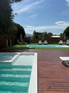 a swimming pool in a yard with a wooden deck at Pousada Encantos do Rosa in Imbituba