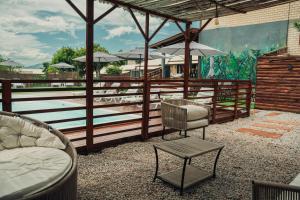 a patio with a bed and a chair and umbrella at Pousada Encantos do Rosa in Imbituba