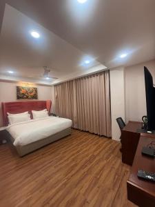 a bedroom with a bed and a desk and a television at HOTEL NILACHAL - 10 Mins Travel to Kamakhya Temple, Guwahati in Guwahati