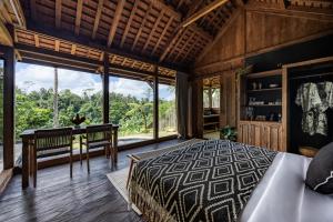 a bedroom with a bed and a desk and windows at Bumi Kabins Ubud in Tegalalang