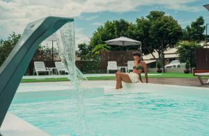 a woman sitting in a pool next to a fountain at Pousada Encantos do Rosa in Imbituba +2 photos