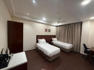 a hotel room with two beds and a desk at HOTEL NILACHAL - 10 Mins Travel to Kamakhya Temple, Guwahati in Guwahati