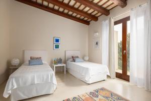 two beds in a white room with a window at Villa Casale by PosarelliVillas in Bisciano +59 photos