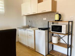 a small kitchen with white cabinets and a microwave at Bay Horizon View in Igalo