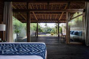 a bedroom with a bed and a view of a patio at Bumi Kabins Ubud in Tegalalang