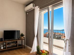 a living room with a television and a balcony at Bay Horizon View in Igalo