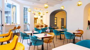 a restaurant with tables and blue chairs at Pilvax Hotel Budapest in Budapest