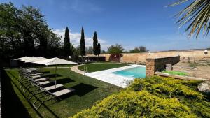 a pool with chairs and umbrellas in a yard at Hospedería del Monasterio de Rueda in Sástago