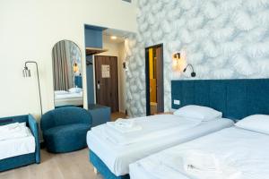a bedroom with two beds and a chair and a mirror at Pilvax Hotel Budapest in Budapest