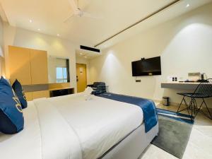 ein Schlafzimmer mit einem großen weißen Bett und einem Fernseher in der Unterkunft Hotel Kyzen - Hitec city, Hyderabad in Hyderabad