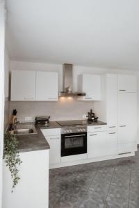 a white kitchen with white cabinets and a sink at Riedwohnung 2 in Lustenau