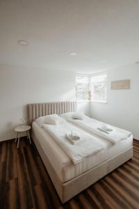 a white bedroom with a large bed and a table at Riedwohnung 2 in Lustenau